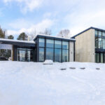 Eine riesige Fensterfront gibt bei diesem Wohnhaus in Kanada von SGD A - Architecture + Design den Blick frei auf die umliegende Landschaft.