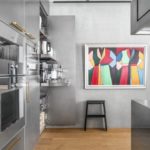 Edelstahlküche mit verborgenen Elektrogeräten und einem modernen Gemälde