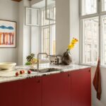 Im der Wohnung von Céline Hallas besticht die Küche durch einen mutigen Materialmix und das starke, kühne Rot der Linoleum-Küchenfronten.